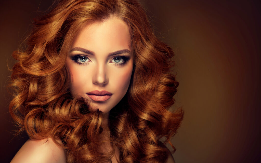 Girl model with long curly red hair . Trendy image of a red head woman